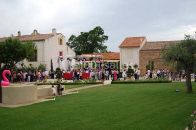 Vue aérienne d'une fête nocturne en extérieur avec éclairages violets, scène musicale et invités rassemblés.