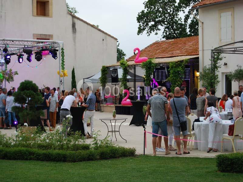 Personnes rassemblées dans une cour extérieure décorée pour un événement festif, avec éclairages et tables dressées.