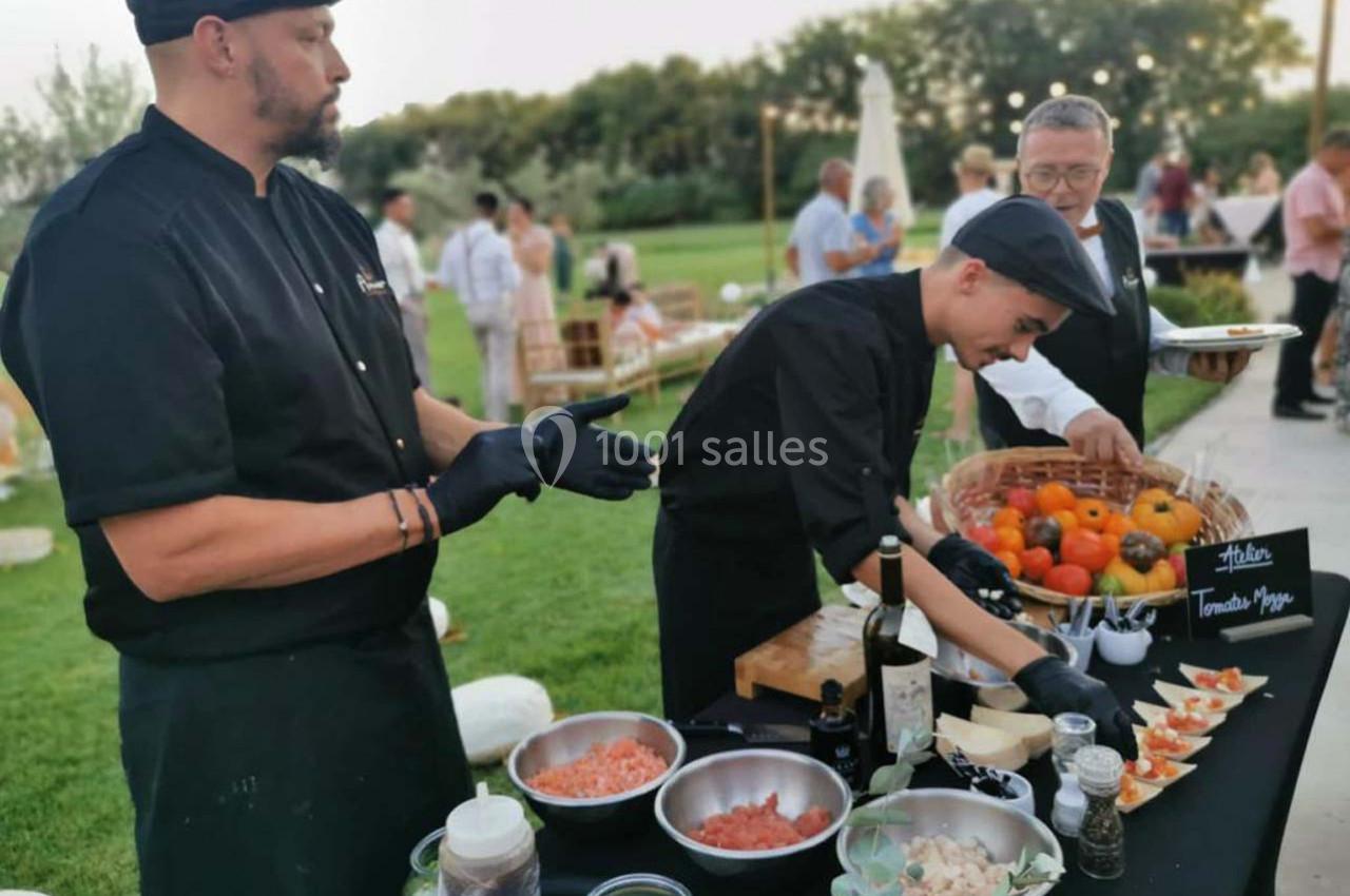 Des chefs préparent et présentent des amuse-bouches sur une table en extérieur lors d'un événement convivial.
