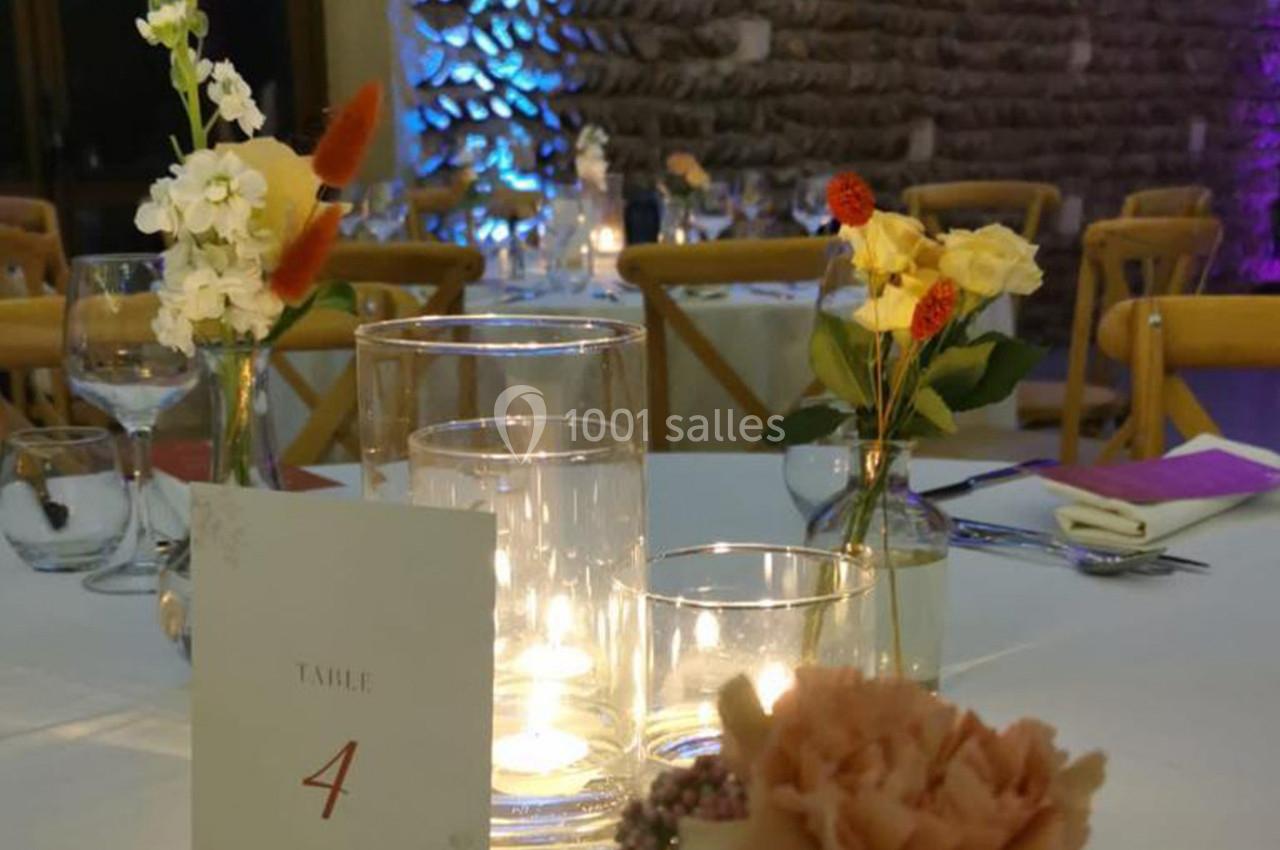 Table décorée pour un événement avec bougies, fleurs et une carte indiquant ’Table 4’ dans une ambiance tamisée.