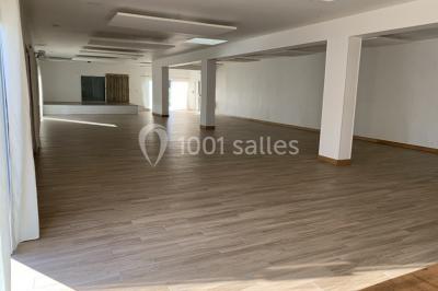 Salle de réception décorée avec des tables dressées, nappes blanches, chaises ornées de nœuds violets et centres de table…