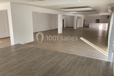 Salle de réception décorée avec des tables dressées, nappes blanches, chaises ornées de nœuds violets et centres de table…