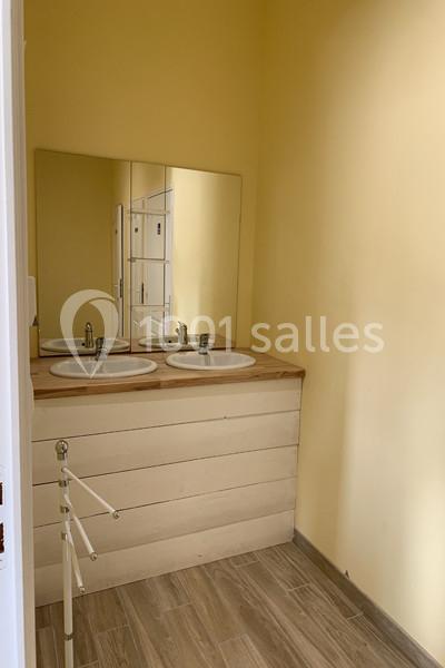 Deux lavabos avec un plan de travail en bois clair, un grand miroir et des murs jaunes dans une petite salle d'eau.