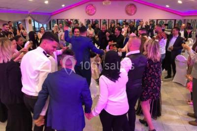 Cuisine professionnelle équipée avec lave-vaisselle industriel, réfrigérateur, plan de travail et cuisinière en inox.