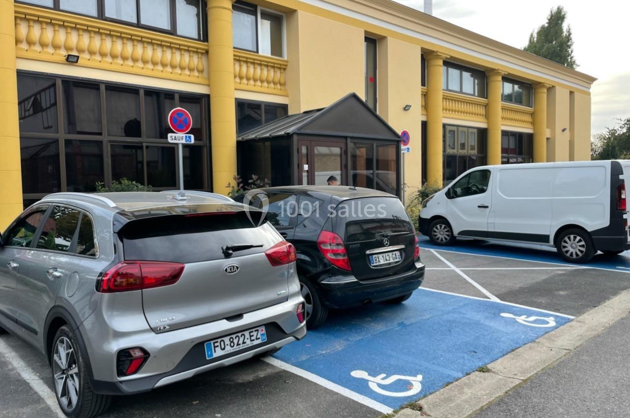 Deux voitures stationnées sur des places réservées aux personnes handicapées devant un bâtiment jaune.