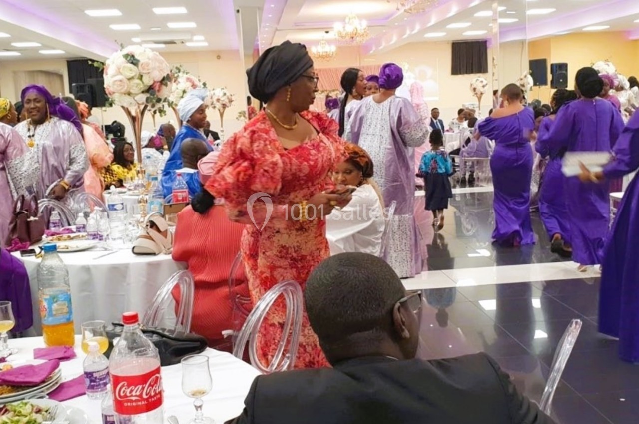 Des personnes en tenue traditionnelle colorée dans une salle de réception décorée, lors d'un événement festif.