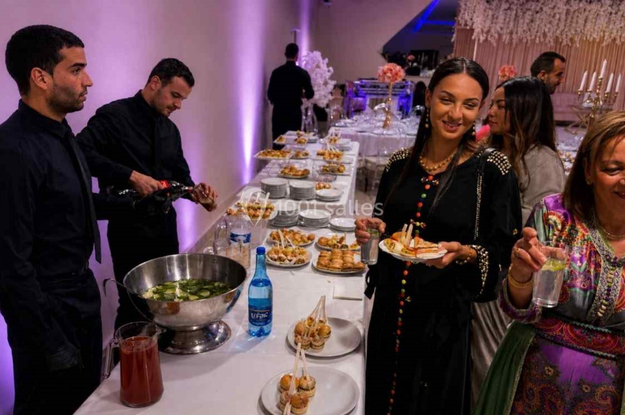 Des convives se servent à un buffet lors d'un événement, avec des serveurs en arrière-plan.