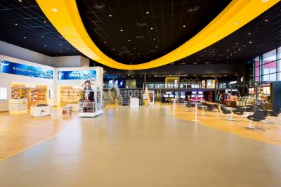 Salle de cinéma avec sièges rouges vides et grand écran affichant le logo IMAX.
