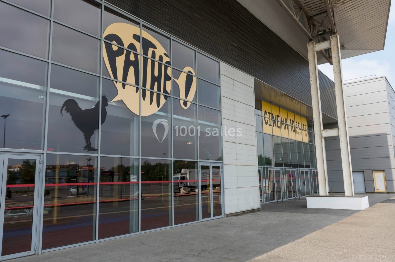 Façade vitrée d'un cinéma avec le logo Pathé et un coq noir, entrée principale visible sous un auvent.