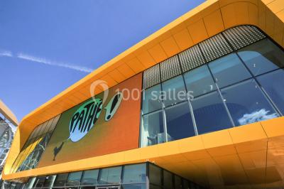 Couloir moderne avec signalétique lumineuse jaune indiquant les salles de cinéma 10 et 12, et des panneaux directionnels.