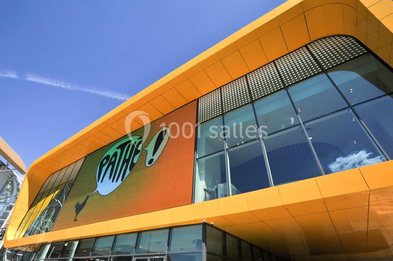 Façade moderne d'un cinéma avec une enseigne ’Pathé !’ sur un écran lumineux, ciel bleu en arrière-plan.