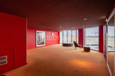Salle de cinéma vide avec des rangées de sièges rouges, éclairage tamisé et écran en fond.