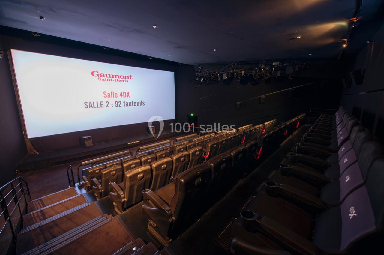 Salle de cinéma vide avec des sièges inclinables et un écran affichant des informations sur la salle 4DX.