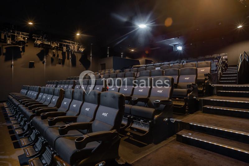 Salle de cinéma vide avec sièges inclinables 4DX, éclairage tamisé et projecteurs suspendus au plafond.