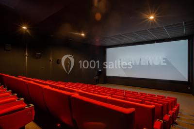 Salle de cinéma vide avec sièges inclinables 4DX, éclairage tamisé et projecteurs suspendus au plafond.