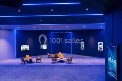 Façade d'un bâtiment moderne avec des enseignes de cinéma IMAX et 4DX, entouré d'une pelouse et d'arbustes.