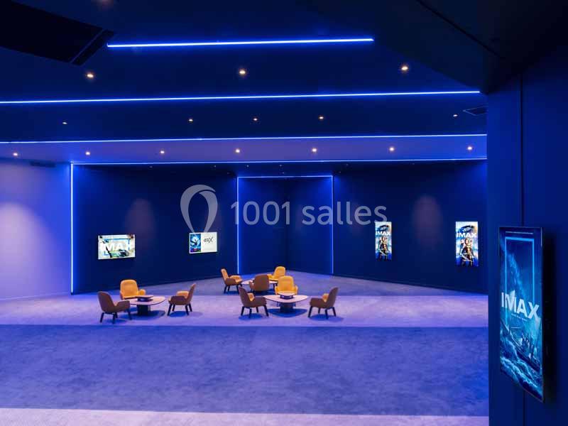 Salle d'attente moderne avec éclairage bleu, fauteuils et tables basses, affiches de films IMAX aux murs.