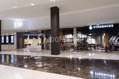 Façade d'un bâtiment moderne avec des enseignes de cinéma IMAX et 4DX, entouré d'une pelouse et d'arbustes.