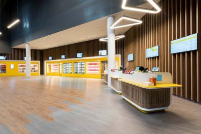 Façade d'un bâtiment moderne avec des enseignes de cinéma IMAX et 4DX, entouré d'une pelouse et d'arbustes.