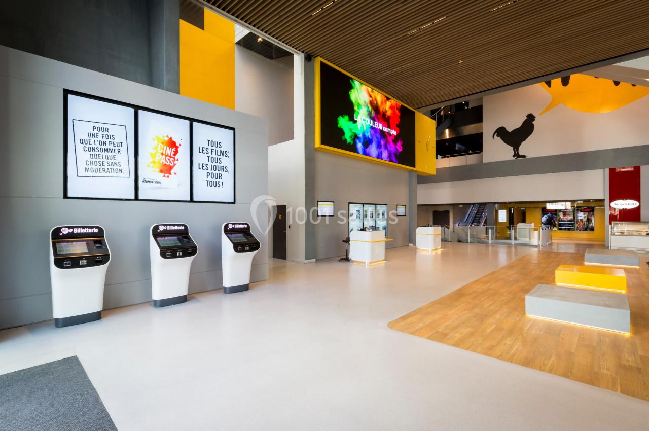 Hall moderne avec bornes interactives, affiches murales, écrans numériques et espaces d’accueil lumineux.