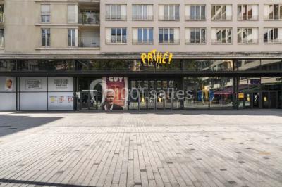 Salle de cinéma vide avec des rangées de sièges rouges et un écran allumé au fond.