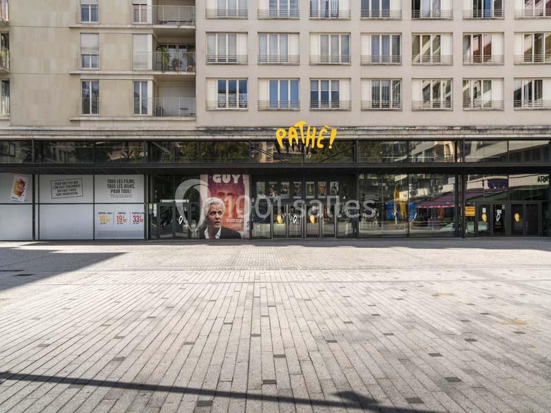 Façade d'un cinéma Pathé avec une affiche de film visible, située devant une place pavée.