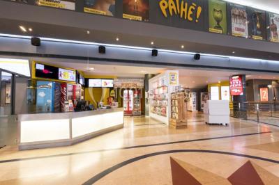 Salle de cinéma vide avec des rangées de sièges rouges et un écran allumé au fond.