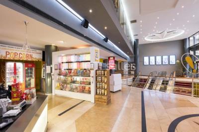 Salle de cinéma vide avec des rangées de sièges rouges et un écran allumé au fond.