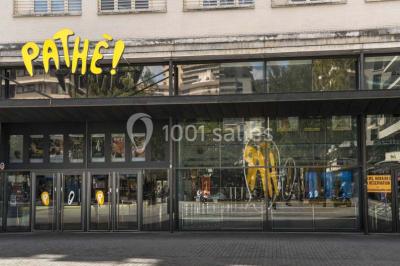 Salle de cinéma vide avec des rangées de sièges rouges et un écran allumé au fond.