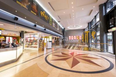 Salle de cinéma vide avec des rangées de sièges rouges et un écran allumé au fond.