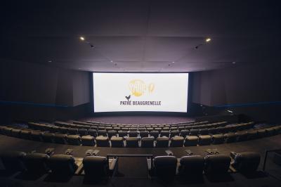 Salle de cinéma vide avec des rangées de sièges rouges et un éclairage tamisé sur les murs.