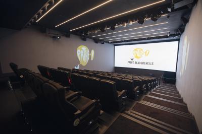 Salle de cinéma vide avec des rangées de sièges rouges et un éclairage tamisé sur les murs.