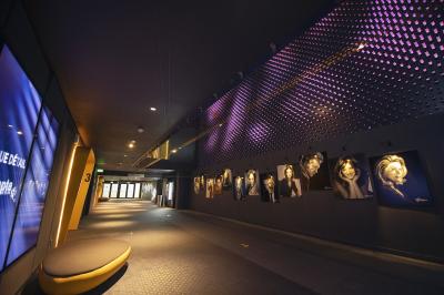 Salle de cinéma vide avec des rangées de sièges rouges et un éclairage tamisé sur les murs.
