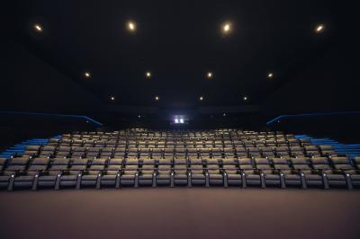 Salle de cinéma vide avec des rangées de sièges rouges et un éclairage tamisé sur les murs.