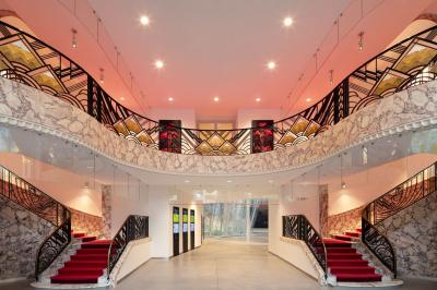 Salle de réunion avec table ronde en bois, chaises rouges, écran mural noir et fournitures de bureau disposées.