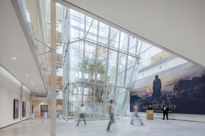 Salle de réunion avec table ronde en bois, chaises rouges, écran mural noir et fournitures de bureau disposées.