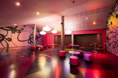 Salle de cinéma vide avec des rangées de fauteuils rouges et un plafond décoré de lumières étoilées.
