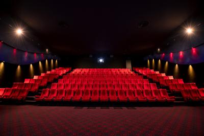 Salle de cinéma vide avec des rangées de fauteuils rouges et un plafond décoré de lumières étoilées.
