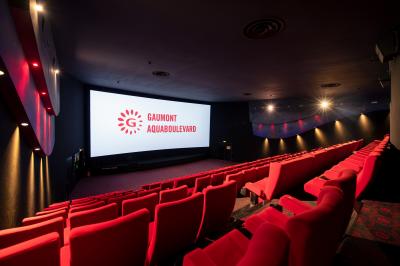 Salle de cinéma vide avec des rangées de fauteuils rouges et un plafond décoré de lumières étoilées.