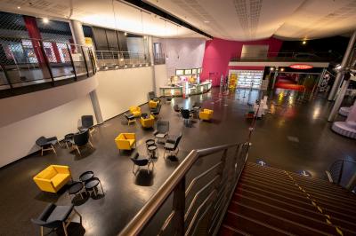 Salle de cinéma vide avec des rangées de fauteuils rouges et un plafond décoré de lumières étoilées.