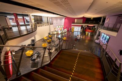 Salle de cinéma vide avec des rangées de fauteuils rouges et un plafond décoré de lumières étoilées.