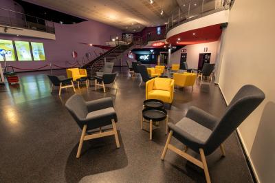 Salle de cinéma vide avec des rangées de fauteuils rouges et un plafond décoré de lumières étoilées.