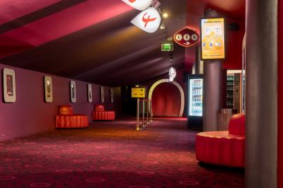 Salle de cinéma vide avec des rangées de fauteuils rouges et un plafond décoré de lumières étoilées.