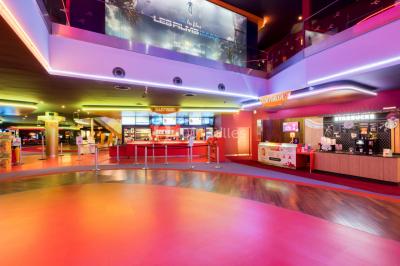 Salle de cinéma vide avec des rangées de sièges rouges et un écran éteint à l'arrière-plan.