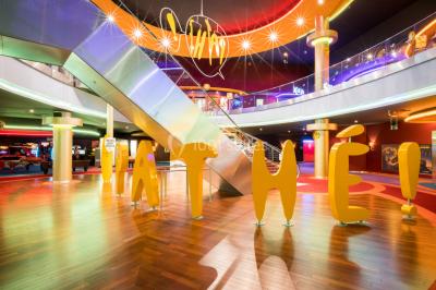 Salle de cinéma vide avec des rangées de sièges rouges et un écran éteint à l'arrière-plan.
