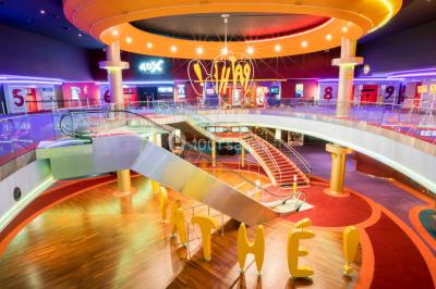 Salle de cinéma vide avec des rangées de sièges rouges et un écran éteint à l'arrière-plan.