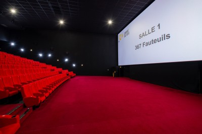 Vue intérieure d'un espace moderne avec escalier, escalator rouge et murs sombres décorés de motifs colorés.