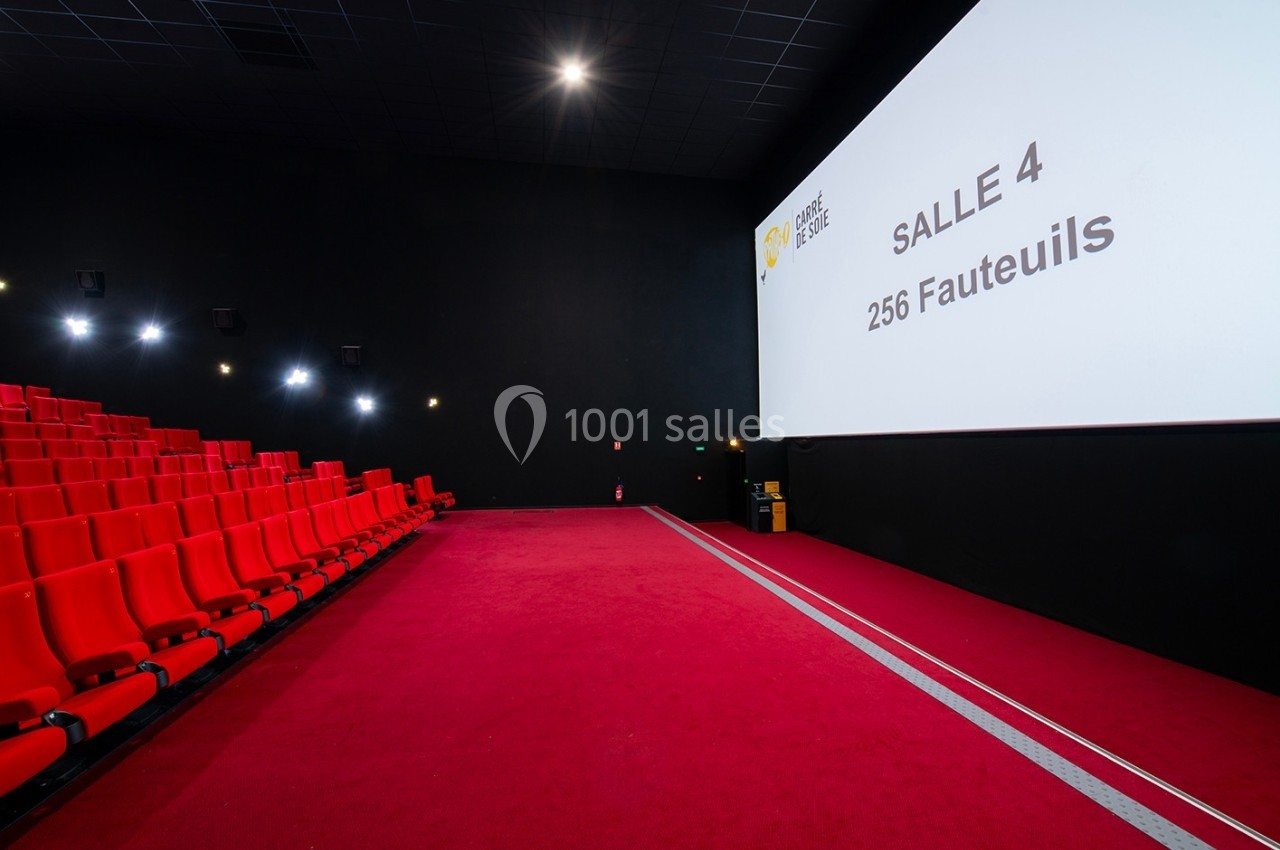 Salle de cinéma vide avec des sièges rouges, un écran affichant ’Salle 4, 256 Fauteuils’ et un éclairage tamisé.