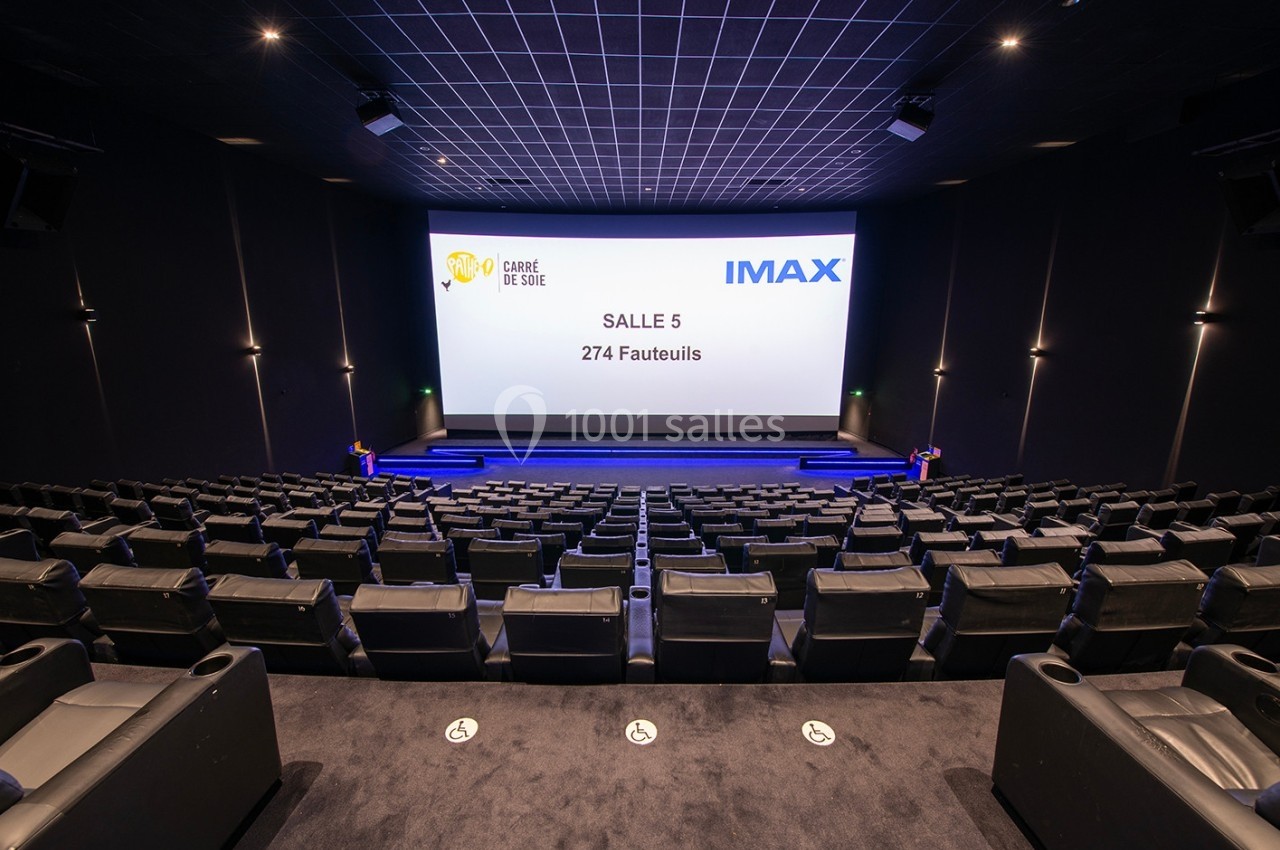 Salle de cinéma IMAX vide avec 274 fauteuils, écran géant et éclairage tamisé.