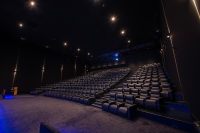 Vue intérieure d'un espace moderne avec escalier, escalator rouge et murs sombres décorés de motifs colorés.